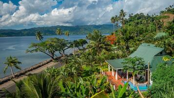 Un resort tropical con piscina, palmeras y vista al mar.