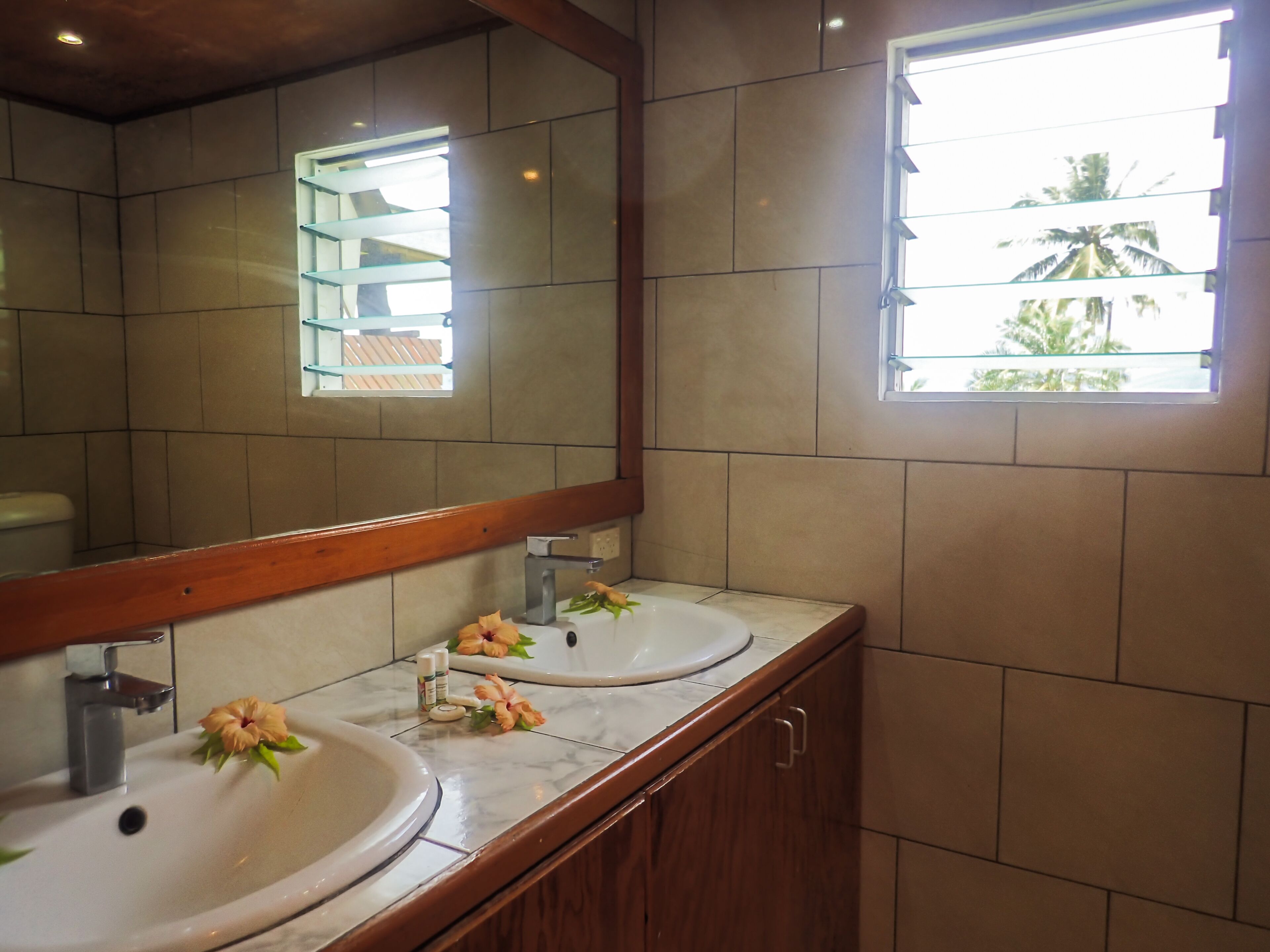 Een badkamer met twee wastafels, een spiegel en een raam.