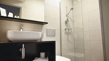A modern bathroom with a glass-enclosed shower, a white sink, and a black vanity.