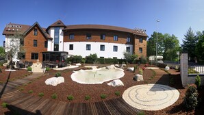 Een hotel met een aangelegde tuin, een vijver en een houten terras.