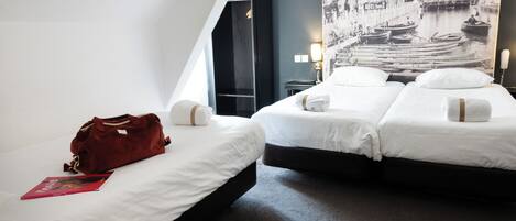 A hotel room with two beds, a red bag, and a wall-mounted lamp.
