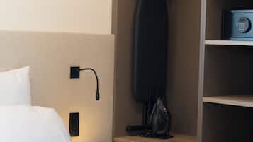 Een hotelkamer met een bed, nachtkastje met een lamp, een magnetron en een kledingroede.