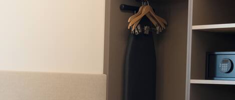 Una habitación de hotel con una cama, una mesita de noche con lámpara, un microondas y un perchero.