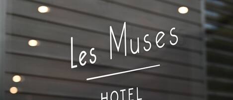 Señal del Hotel Les Muses, con un diseño moderno y líneas horizontales.