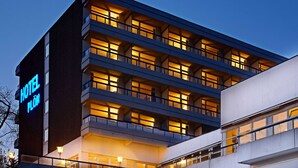 A multi-story hotel with a modern design, featuring balconies and illuminated windows. - Hotel Plöner See by Tulip Inn (Ploen)