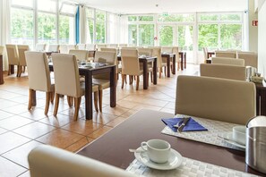 Enjoy meals in this spacious dining area with high ceilings and large windows, perfect for groups.