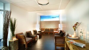 A modern lounge area with wooden furniture, a stone floor, and a large window with a view of the sea. - Hotel Plöner See by Tulip Inn (Ploen)