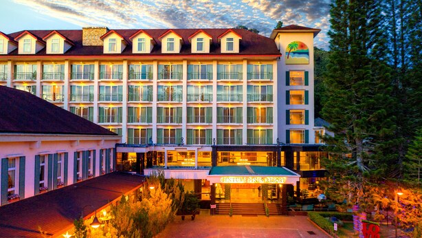 A multi-story hotel with a central entrance, balconies, and a sign reading "CENTURY PINES RESORT".
