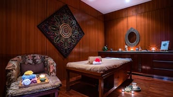 Relax in a cozy space with a plush armchair, ornate tapestry, and a comfortable bed.