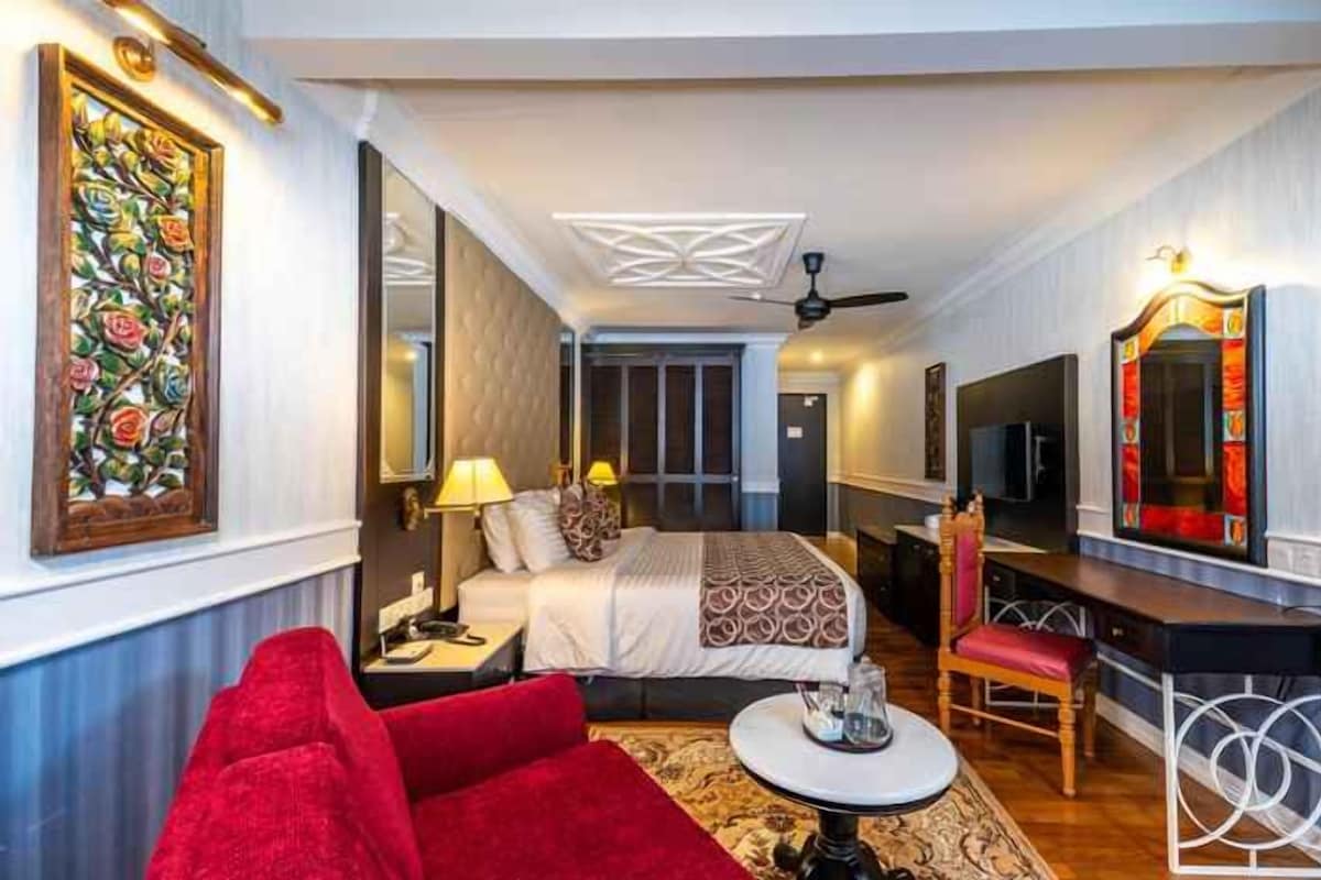 A hotel room with a bed, a desk, a chair, a TV, and a large mirror.
