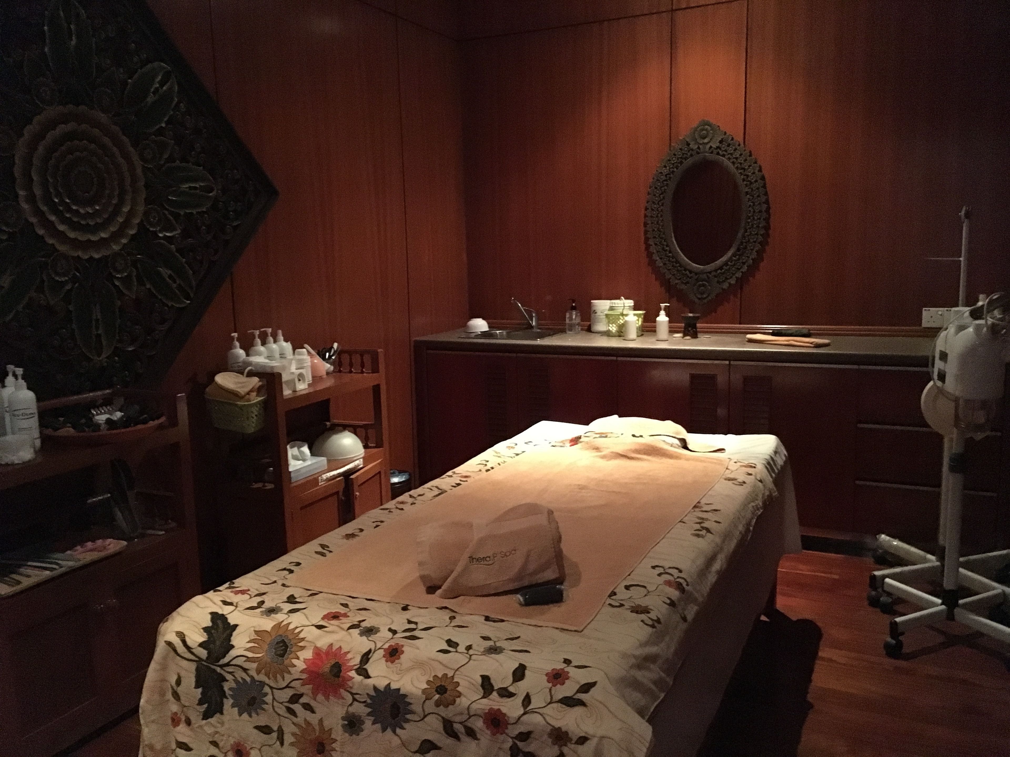 A room with a bed, a wooden cabinet, a mirror, and a sink.