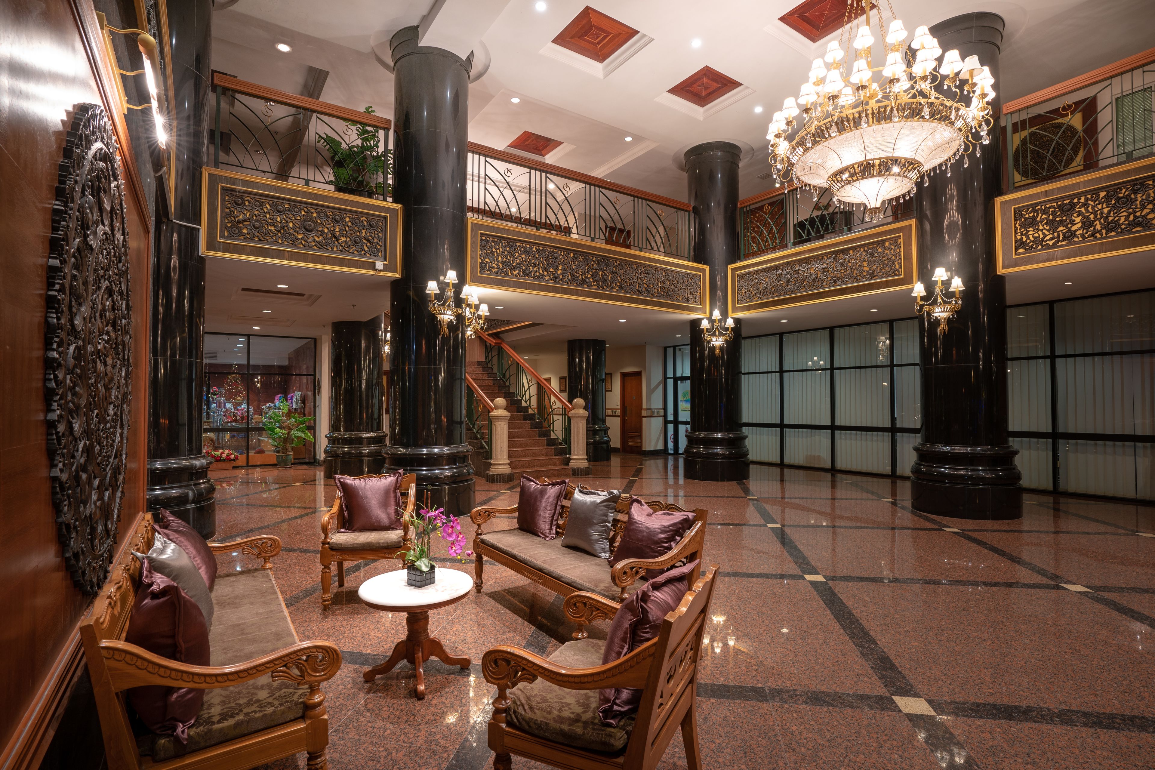 A grand lobby with ornate columns, a chandelier, and a staircase.
