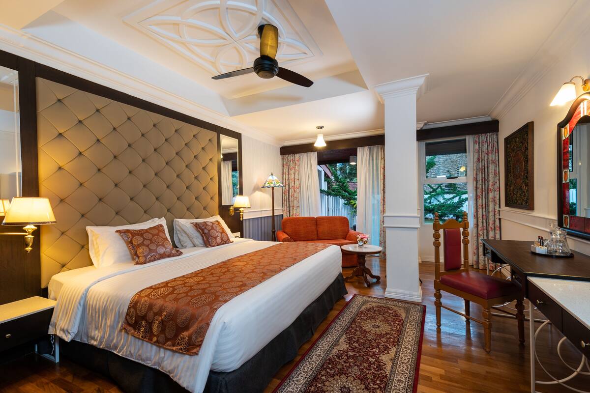 Habitación de hotel con una cama grande, un escritorio, una silla y vistas al exterior.