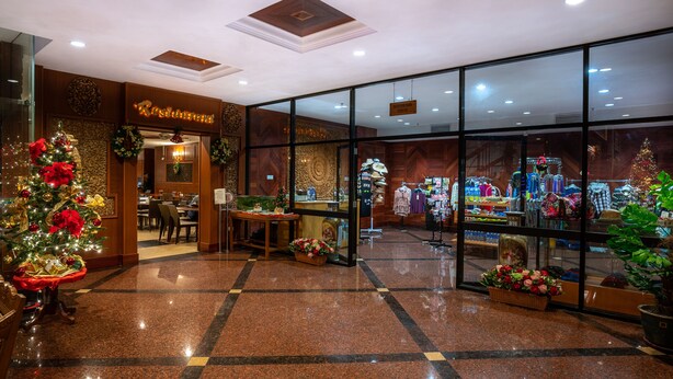 Un vestíbulo de hotel con un árbol de Navidad, un restaurante y una tienda de ropa.