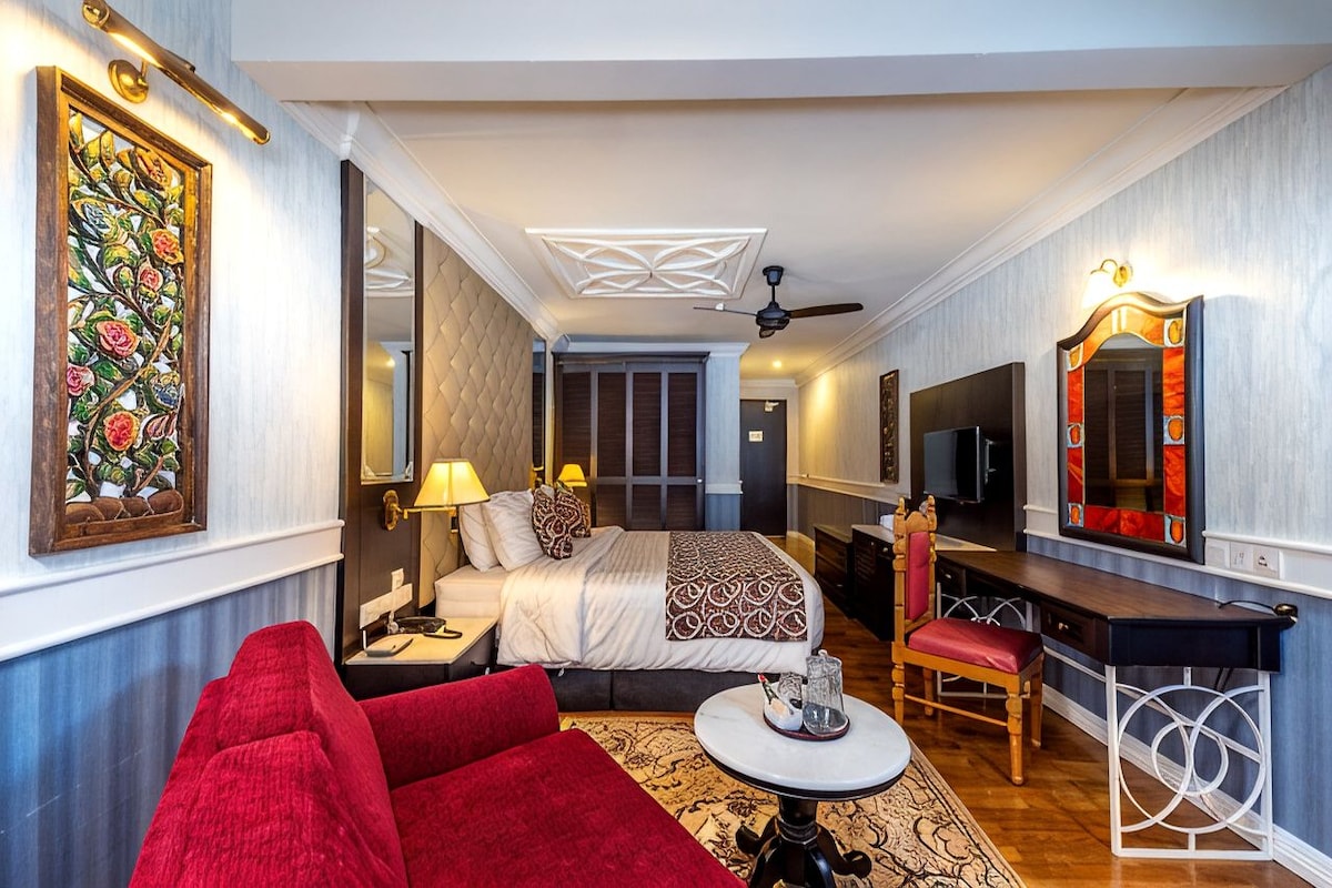 A hotel room with a bed, a desk, a chair, a TV, and a large mirror.