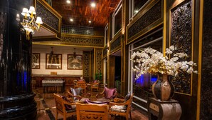 A lobby with ornate decor, including a chandelier, a large vase with white flowers, and a piano.