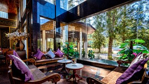 A modern interior with wooden furniture, large windows, and indoor plants.