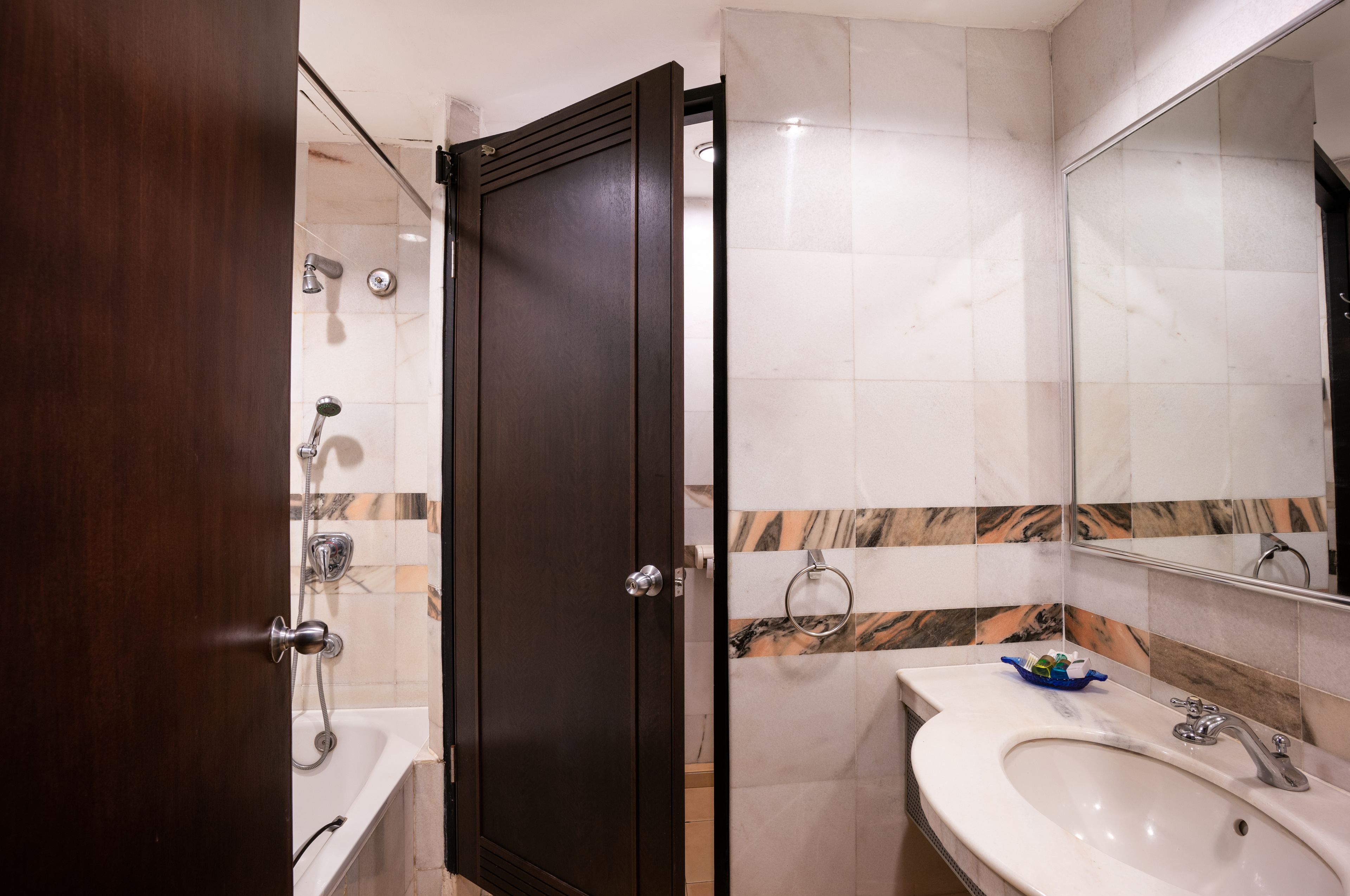 Ein Badezimmer mit Holztür, Badewanne, Waschbecken und Spiegel.