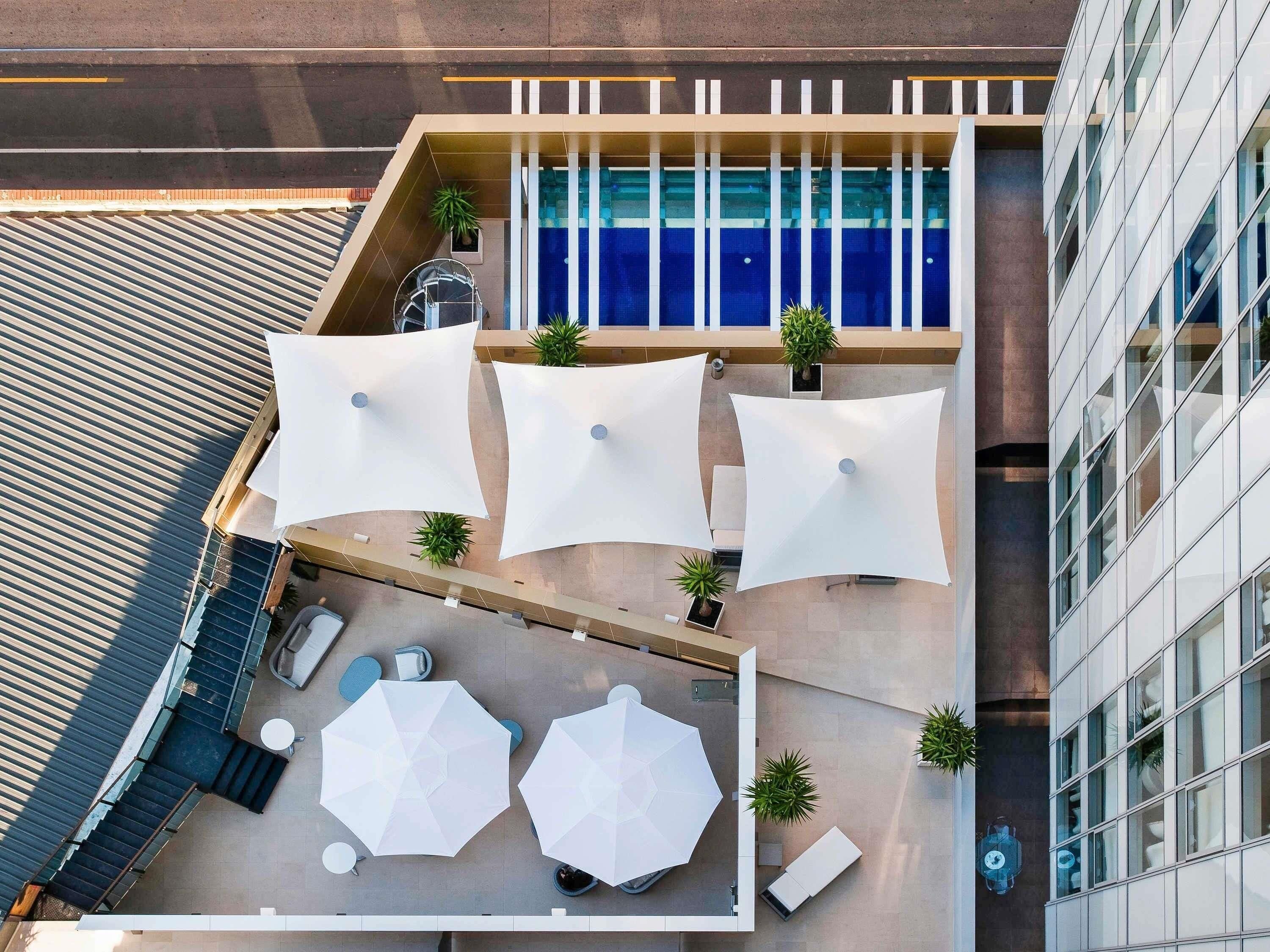 Une terrasse extérieure aménagée avec des sièges, des parasols et des plantes en pot.