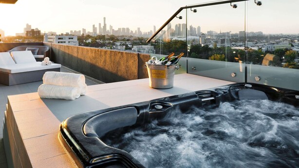 A rooftop terrace with a hot tub, lounge area, and a bucket of champagne bottles.