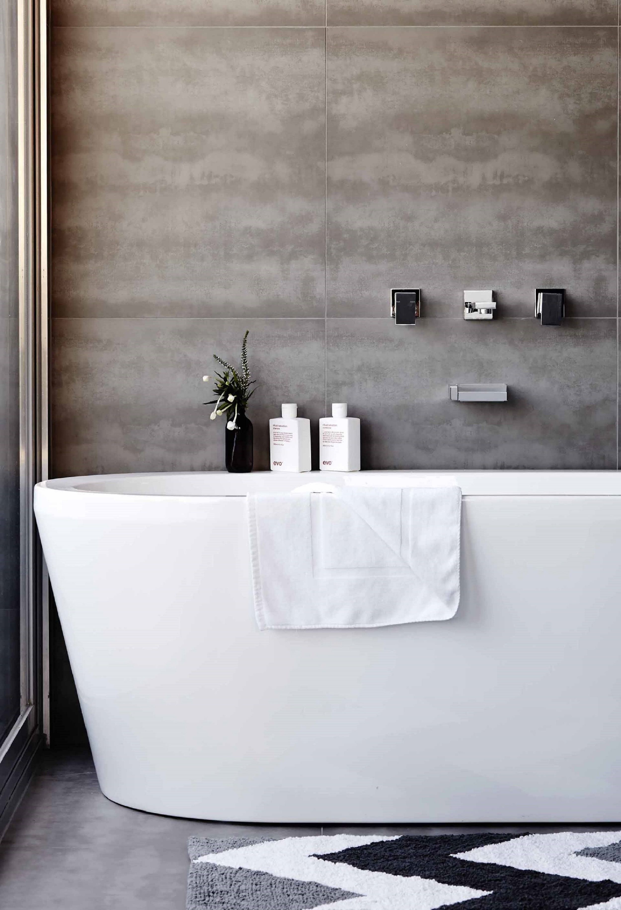 Un bagno moderno con una vasca freestanding, un asciugamano e articoli da toilette a parete.