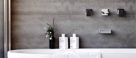 Un bagno moderno con una vasca freestanding, un asciugamano e articoli da toilette a parete.