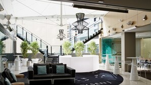 A modern interior with a black sofa, white tables, and potted plants.