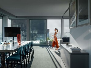 Um interior moderno com área de jantar, TV e grandes janelas com vista para a cidade.