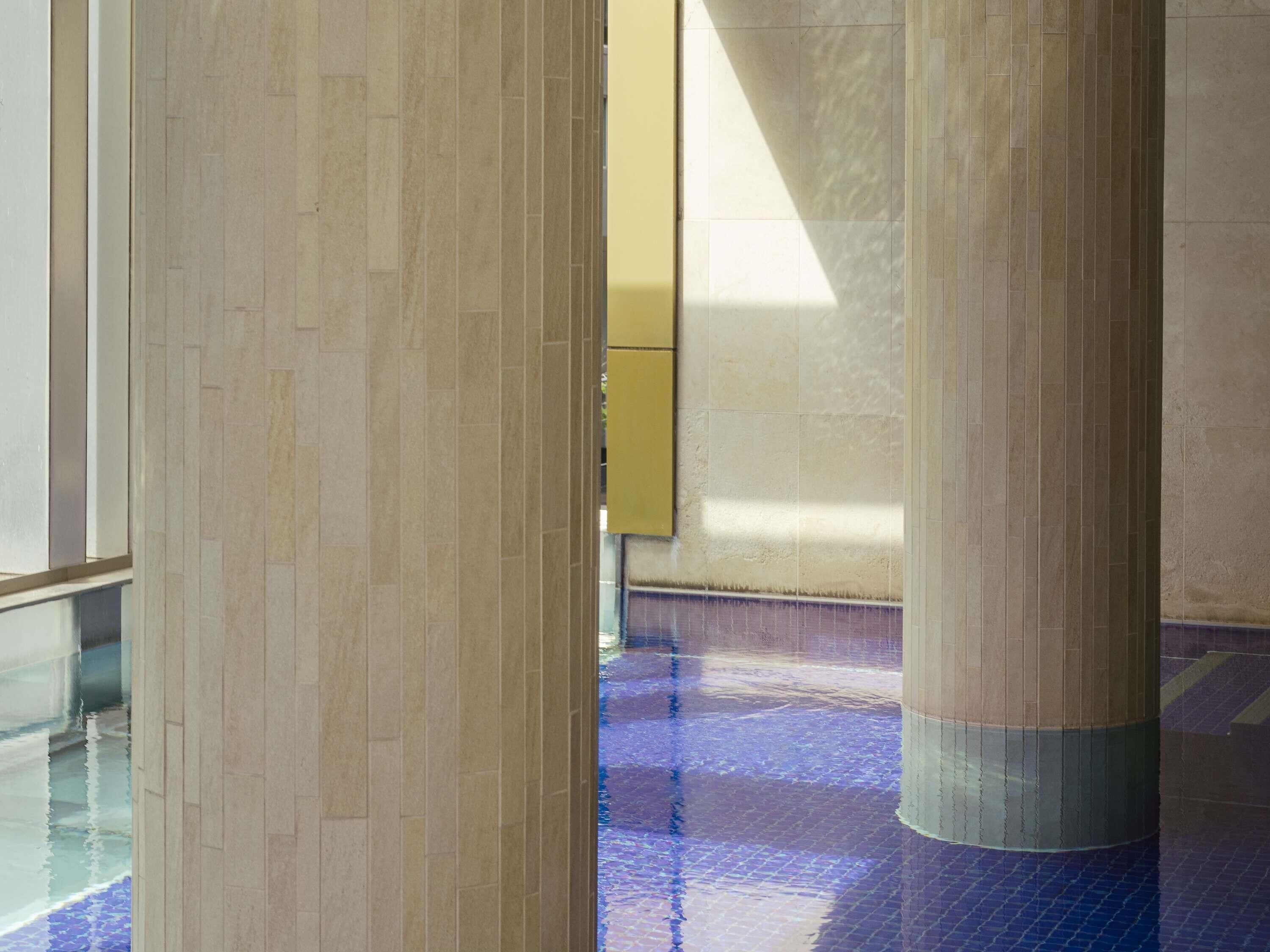 A corridor with tiled flooring and large columns.