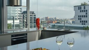 A modern kitchen with a large window, a stainless steel range hood, and a city view.