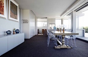 A modern dining area with a long table, clear chairs, and decorative vases. - The Olsen Melbourne - Art Series (South Yarra)