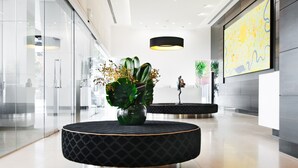 A modern lobby with a round black seating area, a large abstract painting on the wall, and a glass storefront.