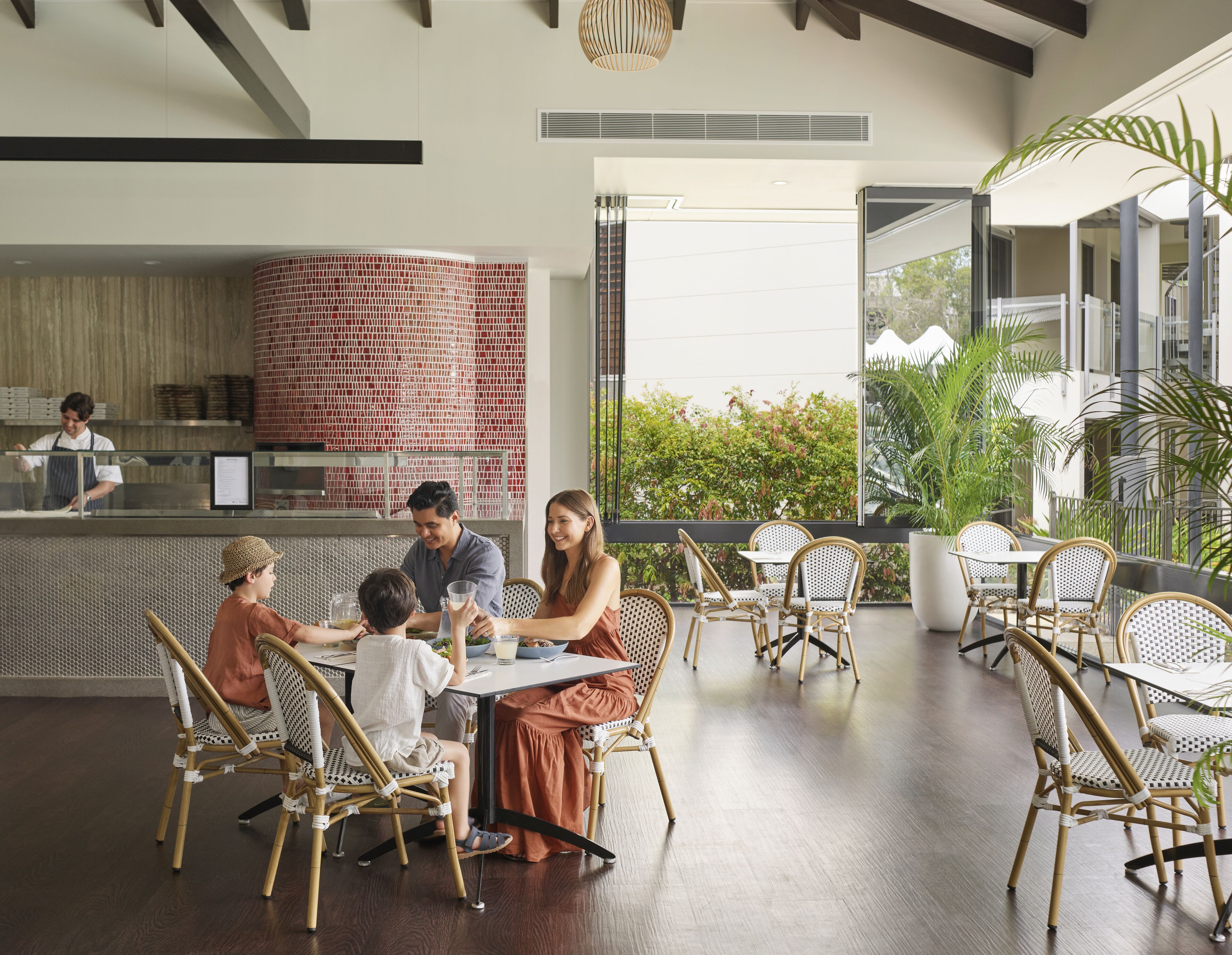 A restaurant with a brick wall, outdoor seating, and a view of greenery.