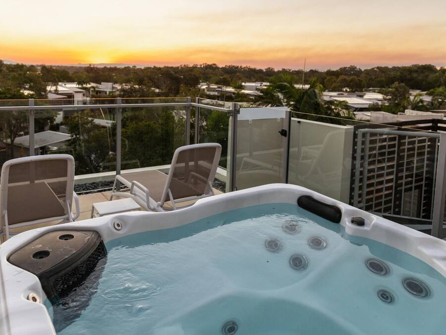 A hot tub with a view of a sunset and residential buildings in the background.