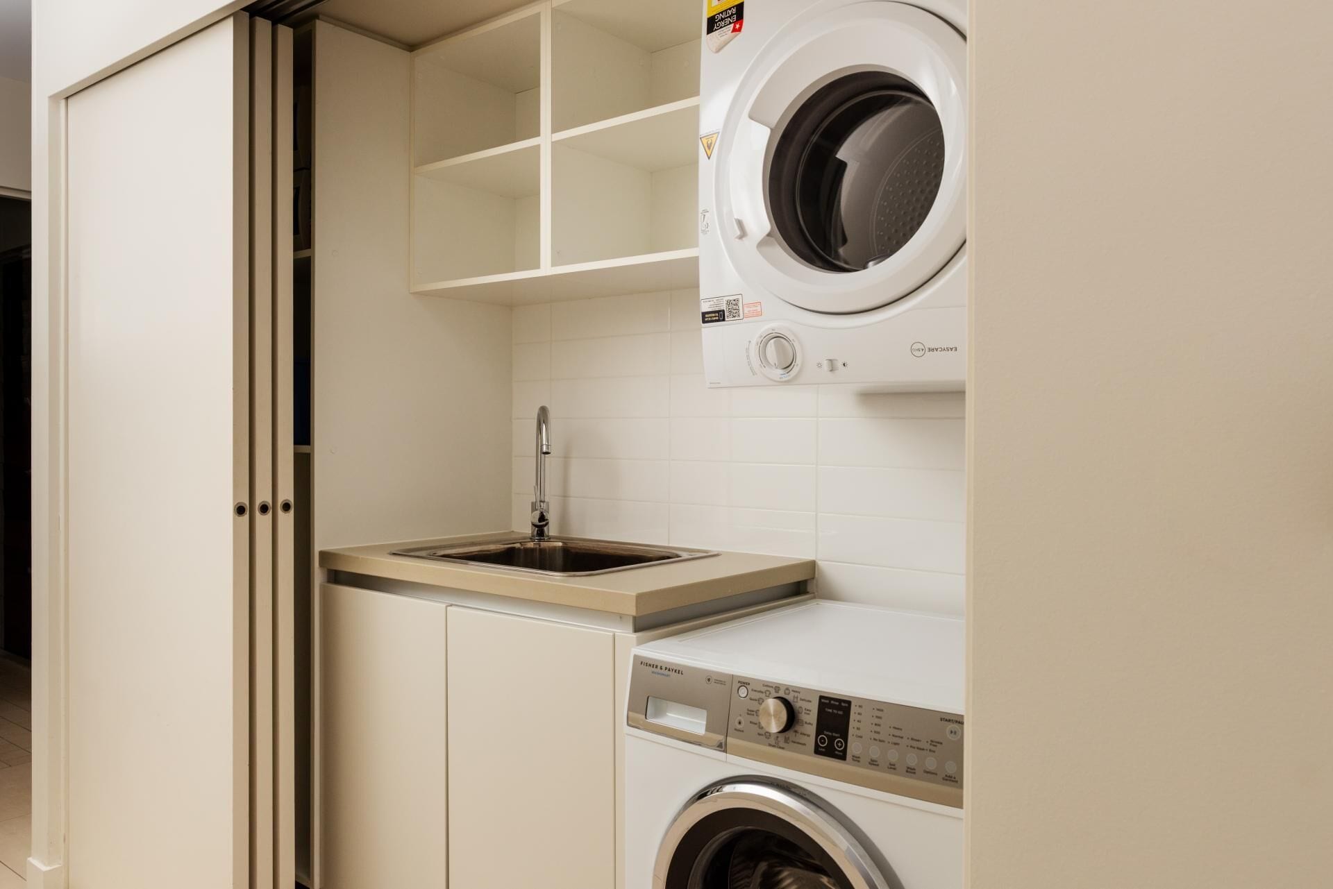 A laundry room with a washing machine, a sink, and a cabinet.