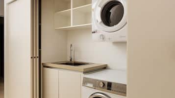 A laundry room with a washing machine, a sink, and a cabinet.