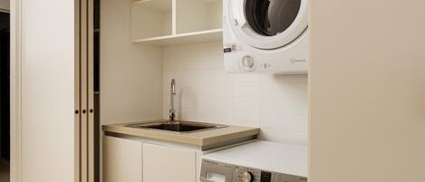 A laundry room with a washing machine, a sink, and a cabinet.