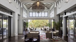 A spacious lobby with a high ceiling, large windows, and a central seating area with sofas and chairs. - RACV Noosa Resort (Noosa Heads)