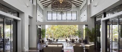 A spacious lobby with a high ceiling, large windows, and a central seating area with sofas and chairs.