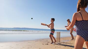 A beach scene with a person playing cricket.