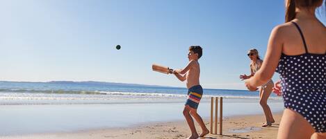 A beach scene with a person playing cricket.