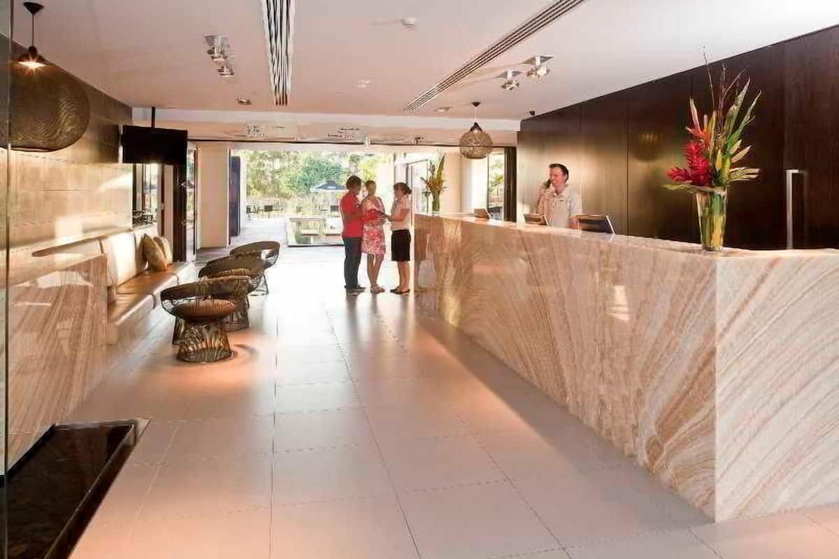 A reception area with a marble counter, seating with cushions, and a large vase of flowers.