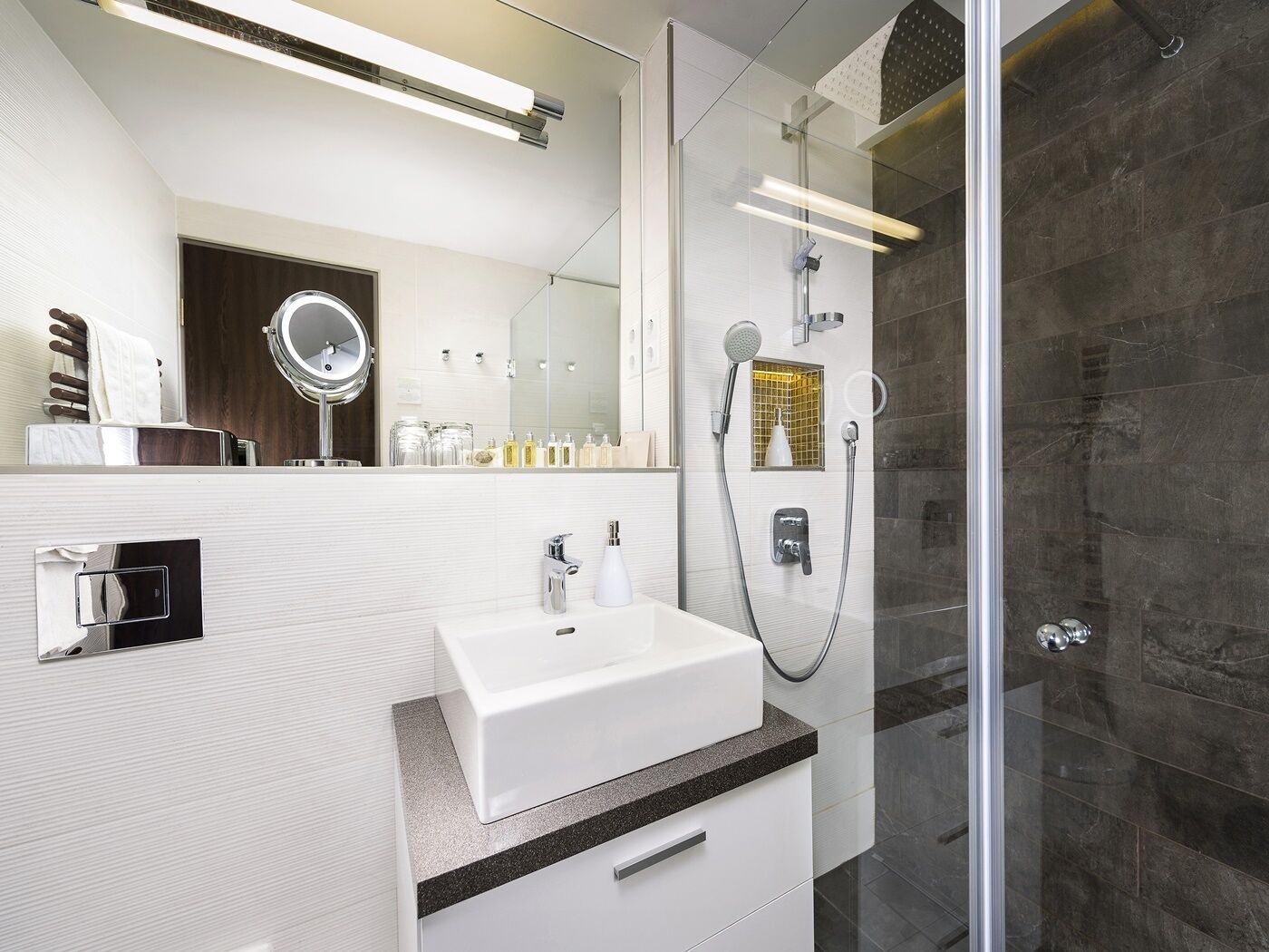 Un baño moderno con lavamanos, espejo y ducha blancos.