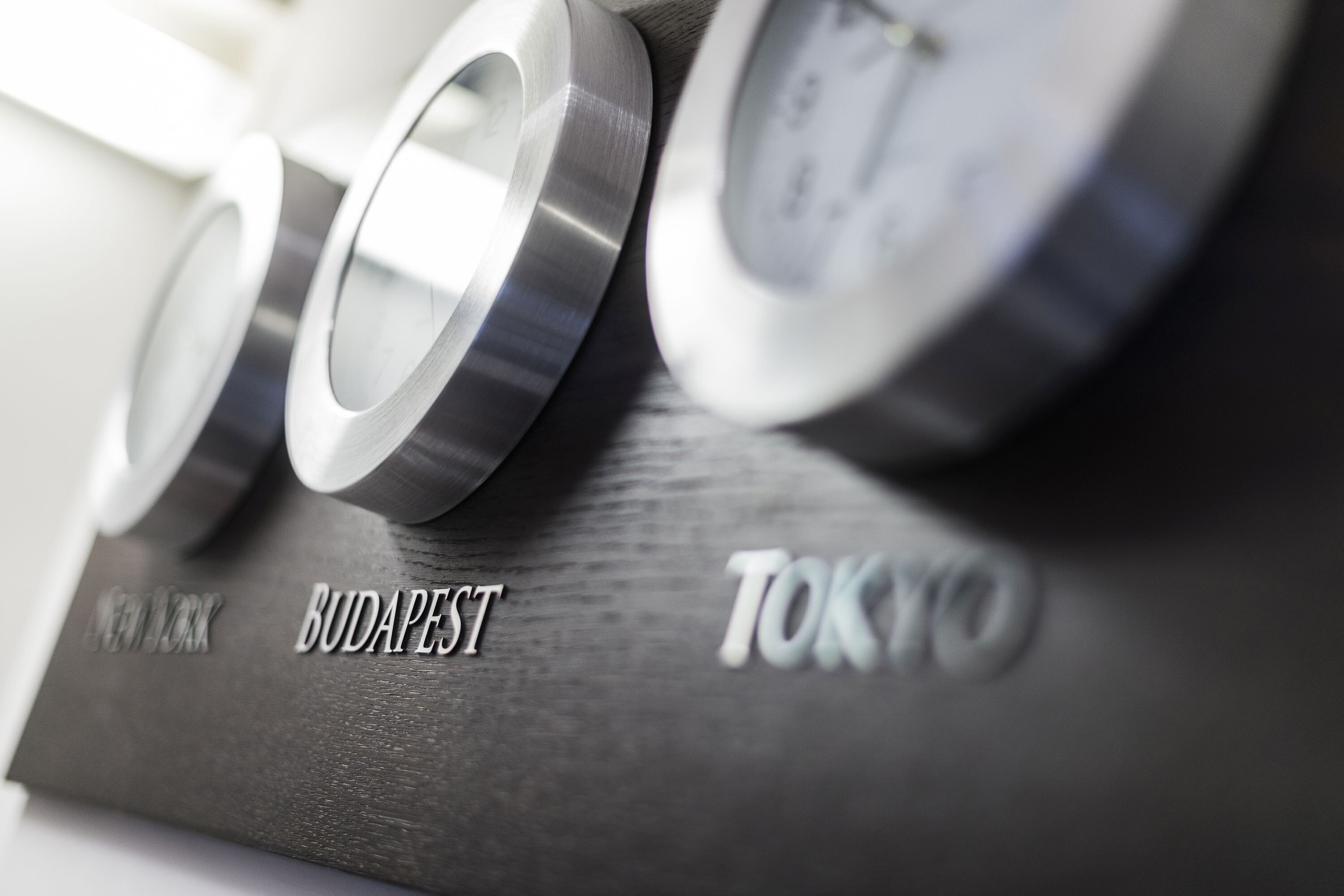 A close-up of a metallic object with embossed text reading "NEW YORK," "BUDAPEST," and "TOKYO."