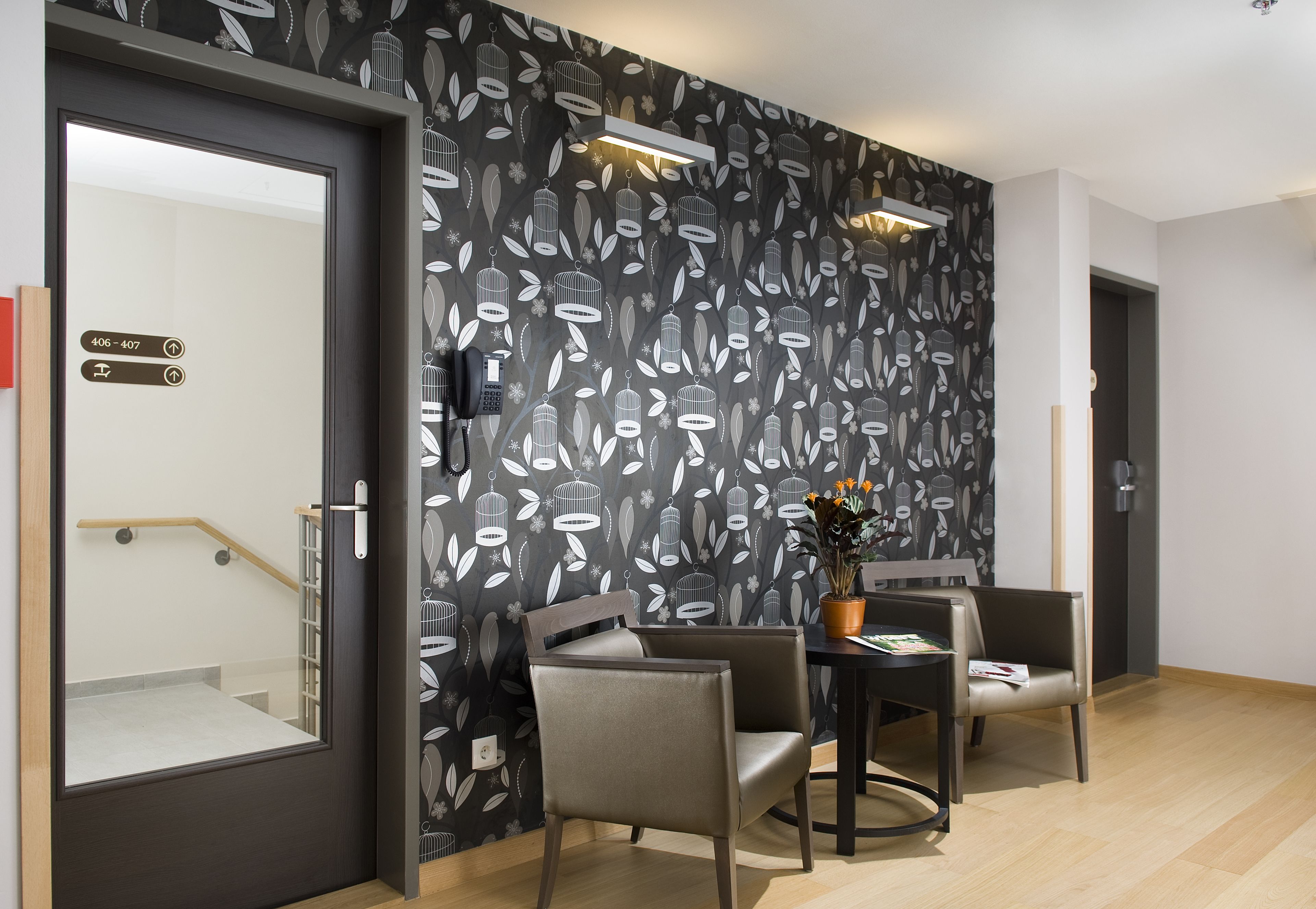 Een moderne kamer met behang met een zwart-wit vogelprint, een houten trap en een eethoek met twee stoelen en een tafel.