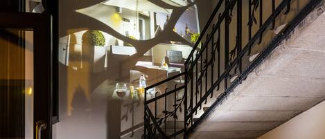 A staircase with a metal railing, a door, and a wall with a window casting shadows.