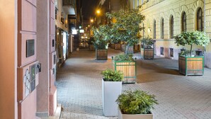 La entrada al Hotel & Apartamentos Opera-Garden, con un corredor cubierto, plantas en macetas y un cartel arriba.