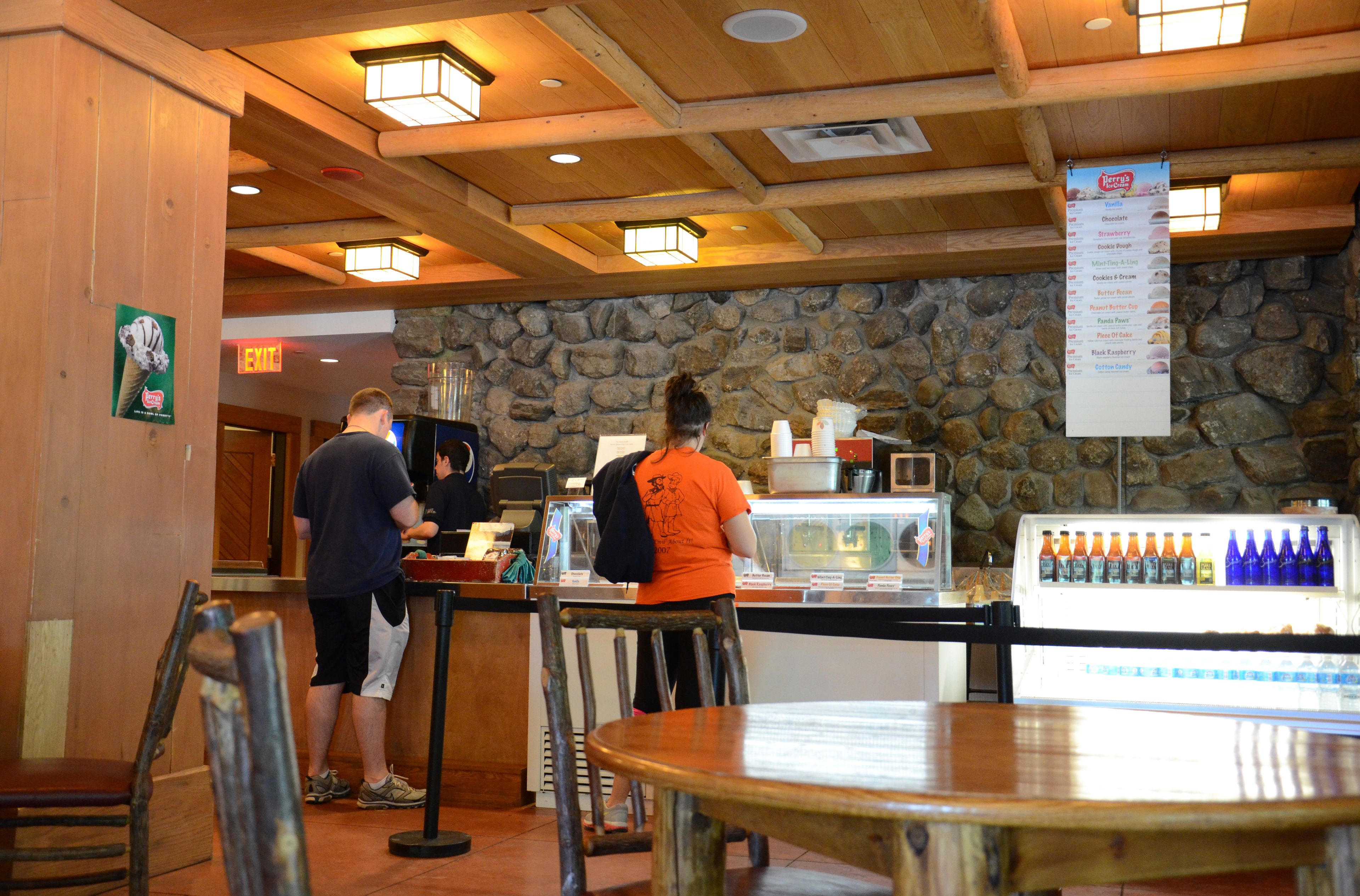 A restaurant interior with a stone wall, wooden ceiling, and a menu hanging from the ceiling.