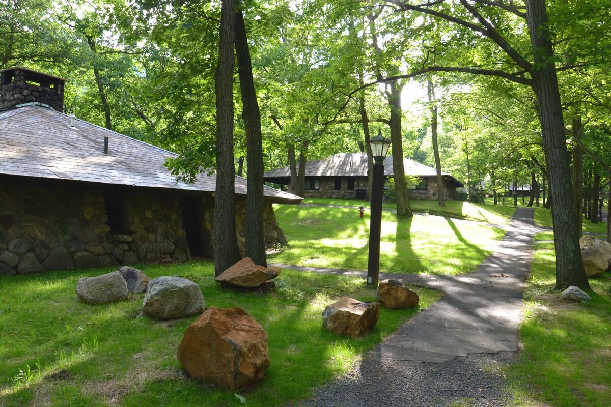 A stone building with a sloped roof, surrounded by large rocks and trees.