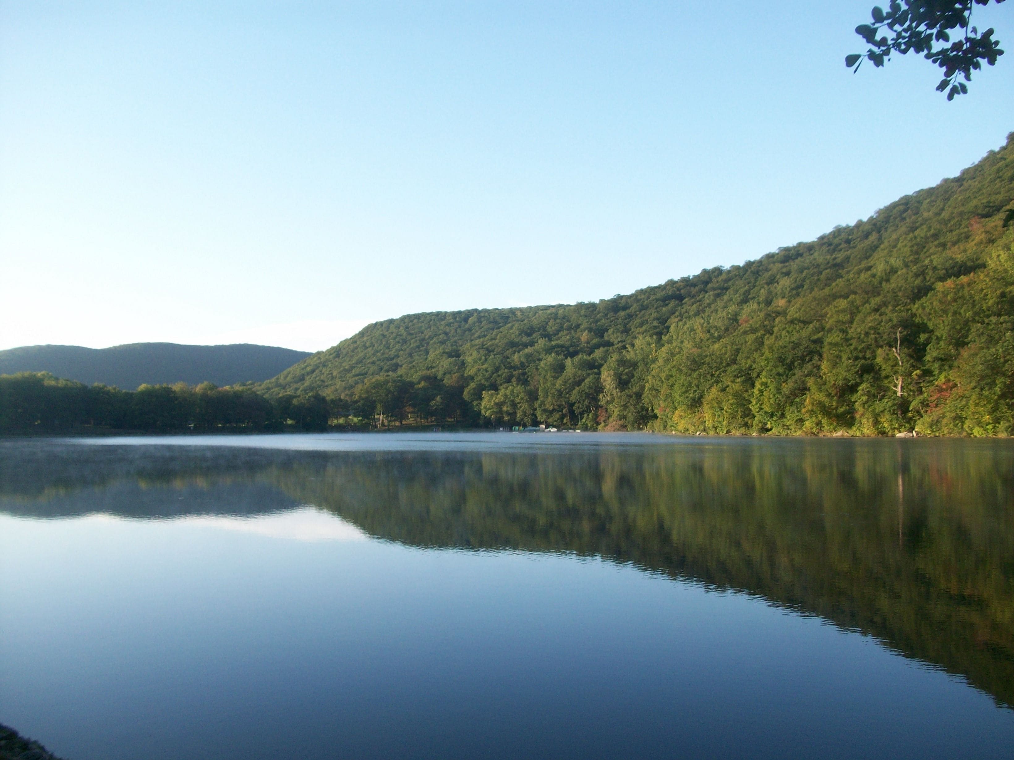 A calm lake surrounded by forested hills.